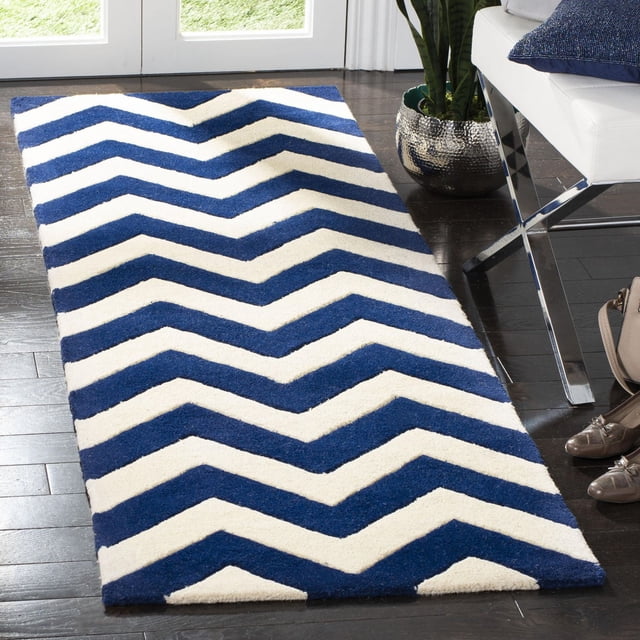 Safavieh Chatham Jake Tapis à Rayures Zigzag avec Laine Tuftée à la Main et Poil Moyen Moelleux, Présentant des Rayures Zigzag Bleu et Blanc Audacieuses sur des Planchers de Bois Franc Sombres dans une Pièce Moderne. Idéal comme Tapis d'Accent pour les Espaces Contemporains, Offrant Douceur et Durabilité, et Convenant aux Entrées Ou aux Aires de Vie.