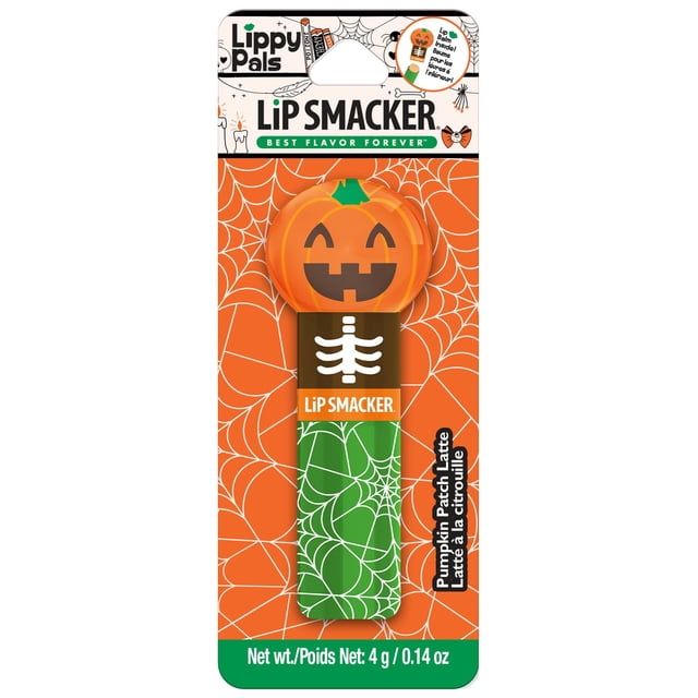 Halloween Lippy Pal Lip Smacker lip balm in pumpkin patch latte flavor with a pumpkin-shaped cap featuring a smiling jack-o'-lantern face and a green tube decorated with white spiderweb patterns, displayed on an orange spiderweb background, suitable as a kids beauty gift set.