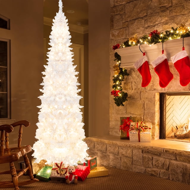 Gymax 7FT Pre-Lit Slim Pencil Christmas Tree Full Artificial Tree w/ LED Lights displayed in a cozy holiday setting. The white PVC tree features 800 branch tips and 300 warm white LED lights with 8 lighting modes, including flashing and twinkling. It stands on a sturdy metal base with anti-slip pads and measures 7 feet tall with a 2.6-foot diameter. The slim pencil shape is ideal for small spaces, and the tree is adorned with wrapped gifts at the base, creating a festive atmosphere.