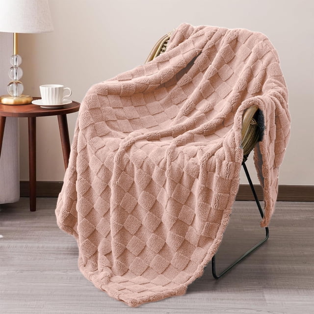 TIMIFIS Throw Blanket Winter Bed Blanket Thermal Throw Blanket Lightweight Bed Throw Breathable Soft Comfortable Machine Washable Blanket for All Season Fleece Blanket, 27X39 In. A soft pink fleece throw blanket with a textured checkered pattern draped over a chair in a cozy room setting. The blanket is lightweight, breathable, and suitable for all seasons, offering warmth and comfort. Perfect for home decor, gifting, or use on beds, sofas, or as a decorative accent.
