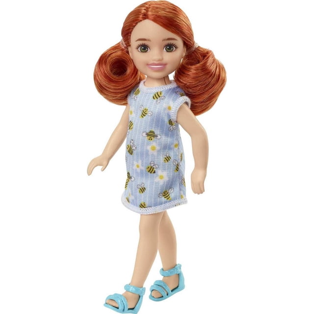 Barbie Chelsea Doll (Red Hair) in Bumblebee Dress is a 6-inch fashion doll wearing a sleeveless light blue knitted dress with yellow and black bumblebee and flower patterns, styled with red hair in pigtails and light blue sandals, suitable for imaginative play and collecting.