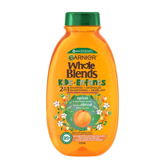 Garnier Whole Blends Kids 2-in-1 Detangling Shampoo Apricot & Cotton Flower 250 mL in an orange translucent bottle with green flip cap, featuring apricot and cotton flower illustrations. Hypoallergenic formula gently cleanses and detangles hair without stinging eyes or causing knots.