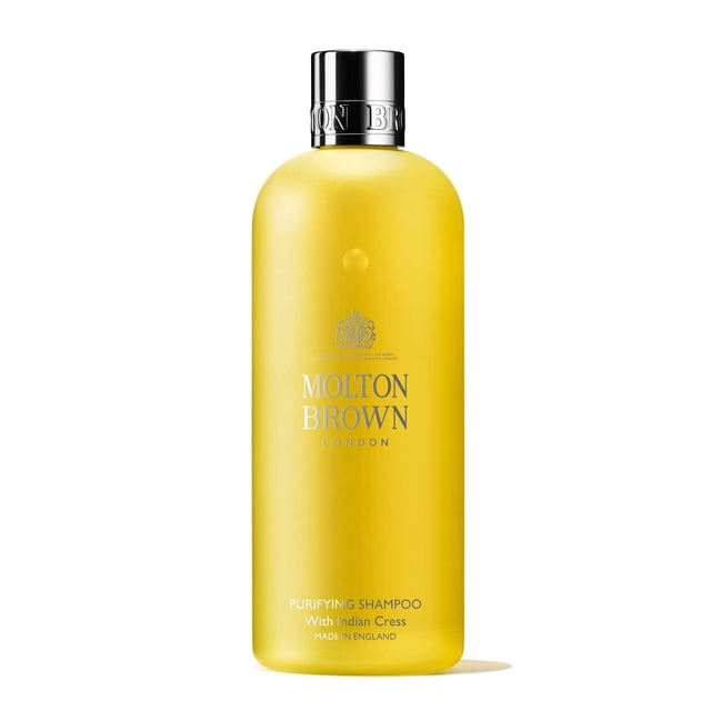 Molton Brown Purifying Shampoo With Indian Cress, 10 fl. oz. bottle. The shampoo is presented in a sleek, cylindrical yellow bottle with a silver cap and embossed brand logo. It features a clear, vegan formula enriched with Indian cress extract, offering floral notes of honeysuckle, sandalwood, and jasmine. Made in England, cruelty-free, and free from parabens.
