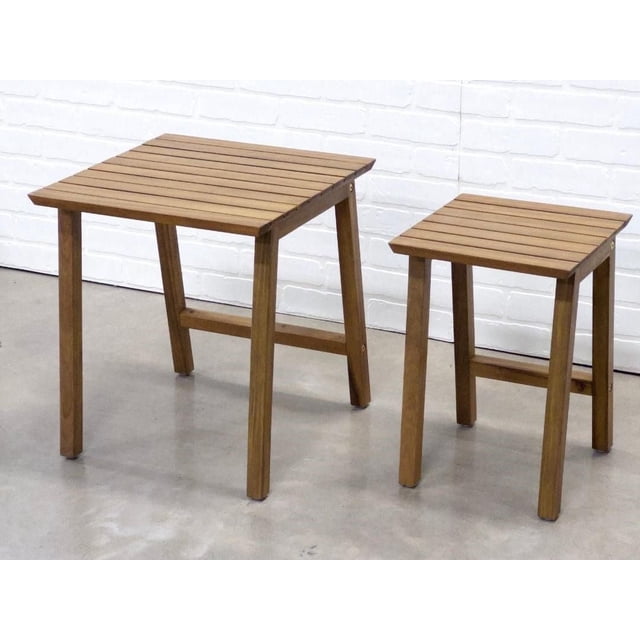 Vario 2 pcs table set made of durable, weather-resistant acacia wood with slatted tops and sturdy legs, featuring one larger and one smaller table on a concrete floor against a white brick wall, ideal for versatile indoor or outdoor use.