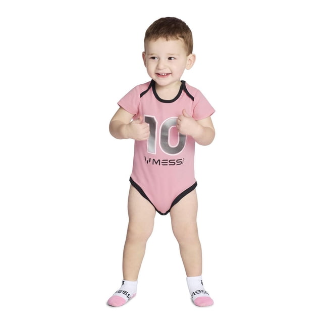 MESSI INFANT SHORT SLEEVE ONESIE in pink 100% cotton interlock with black trim, featuring number 10 and Messi branding on the front, worn by a standing baby boy with matching Messi branded white and pink socks, designed for comfort and breathability.