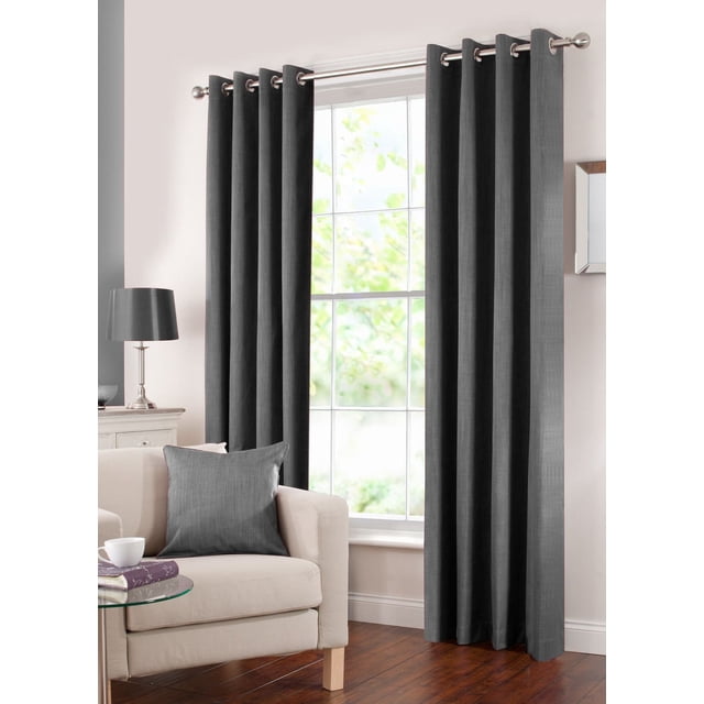 Gouchee Design Solar Blackout Panel in black, two curtain panels with eight silver metal grommets each, made of 100% polyester with acrylic coating and subtle two-tone texture, hanging on a silver rod in a living room with beige armchair, matching black cushion, glass side table, and wooden floor, ideal for blocking sunlight and enhancing privacy.