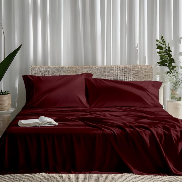 ViscoLogic EGYPTIAN COMFORT Silky Smooth Lightweight Bed Sheet Set in burgundy, full/double size, displayed on a bed with a rattan headboard. Includes 1 flat sheet, 1 fitted sheet with 15-inch deep pockets, and 2 pillowcases. The brushed microfiber material offers a silky, wrinkle-free finish and luxurious softness, ideal for allergy sufferers. Perfect for enhancing bedroom decor, this bedding set is shown in a minimalist room with white curtains and decorative plants.