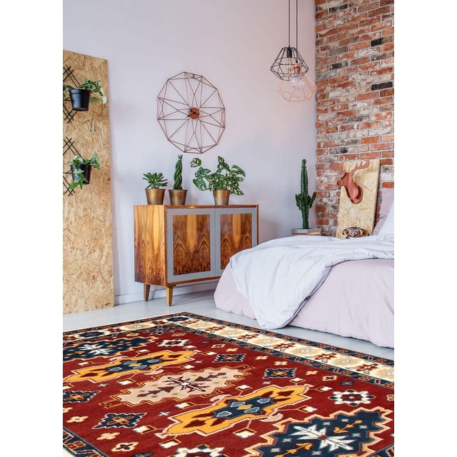ECARPETGALLERY 100% Wool Traditional Indoor Area Rug with bold geometric patterns in red, yellow, navy, and beige, displayed in a bedroom featuring light pink bedding, a wooden cabinet with potted plants, and an exposed brick wall with modern decor, ideal for entrance, bedroom, living, or dining rooms.