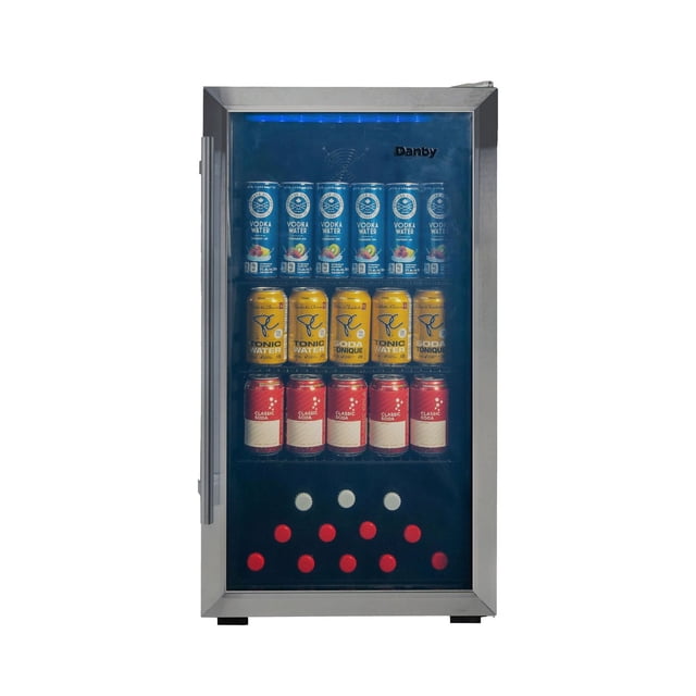 Danby DBC117A2BSSDD-6 3.1 cu. ft. free-standing beverage center in stainless steel with a glass door and blue LED lighting, containing three adjustable shelves stocked with vodka water, tonic water, and classic soda cans, suitable for compact drink storage in home bars or basements.