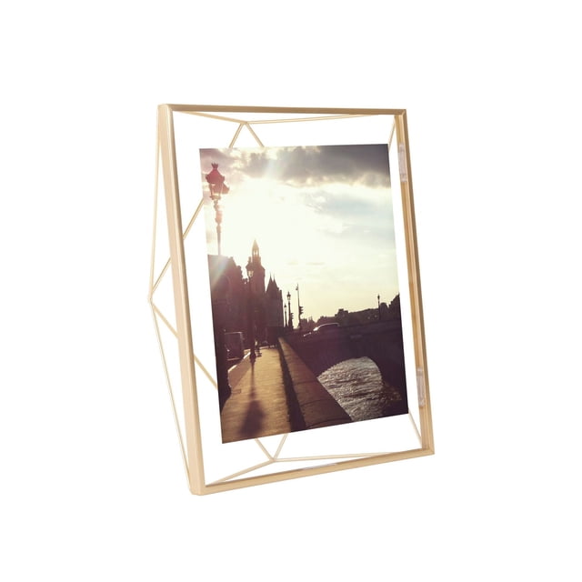 Umbra Prisma Picture Frame in matte brass featuring a geometric wireframe that holds a photo floating between two glass panes. The frame can stand angled on a table or be mounted on a wall, adding dimension and modern style to home décor.