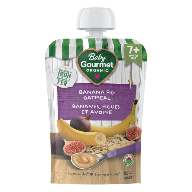 Baby Gourmet Organic Puree Banana Fig Oatmeal pouch with green and white stripes and a white cap, featuring banana, figs, and oatmeal on a wooden surface, suitable for babies 7 months and older, providing 2 grams of fiber and a good source of iron in a 128ml certified organic, non-GMO puree pouch.