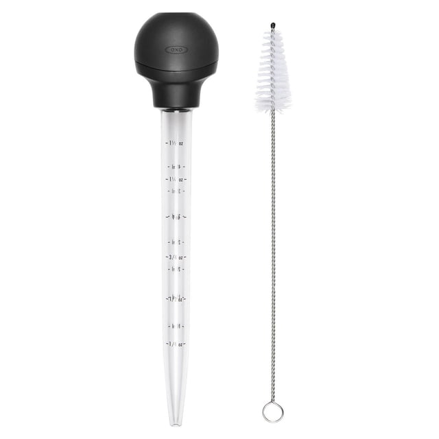 OXO Softworks Turkey Baster with a black non-slip bulb and collar, clear crack-resistant basting tube marked with 1.5 oz (40 mL) capacity in standard and metric units, and a white bristle cleaning brush with metal handle for easy kitchen meat basting.