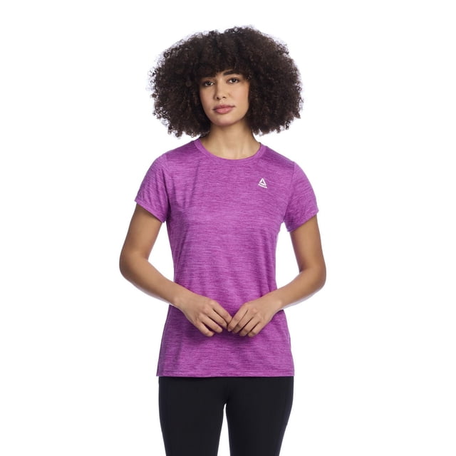 Reebok Women's Legacy Performance Short-Sleeve T-Shirt in purple heather soft jersey fabric with a crew neckline and short sleeves, featuring a minimal white Reebok Delta logo on the left chest, shown in a front-facing view with black athletic leggings, ideal for activewear or casual use.