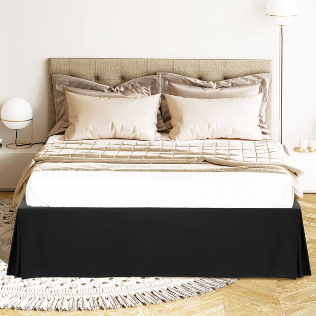 PiccoCasa Bed Skirt Double Brushed Microfiber with Dust Ruffle, King Black. This bed skirt is made of 110 gsm microfiber, offering a thicker, non-see-through, wrinkle-resistant, and durable fabric. It features a 16-inch drop that reaches the floor, hiding under-the-bed storage, and is secured with elastic bands at all four corners for stability. The tailored design includes contemporary corner pleats in a solid black color, complementing various bedroom styles. Shown on a king-size bed in a modern bedroom setting with neutral decor.