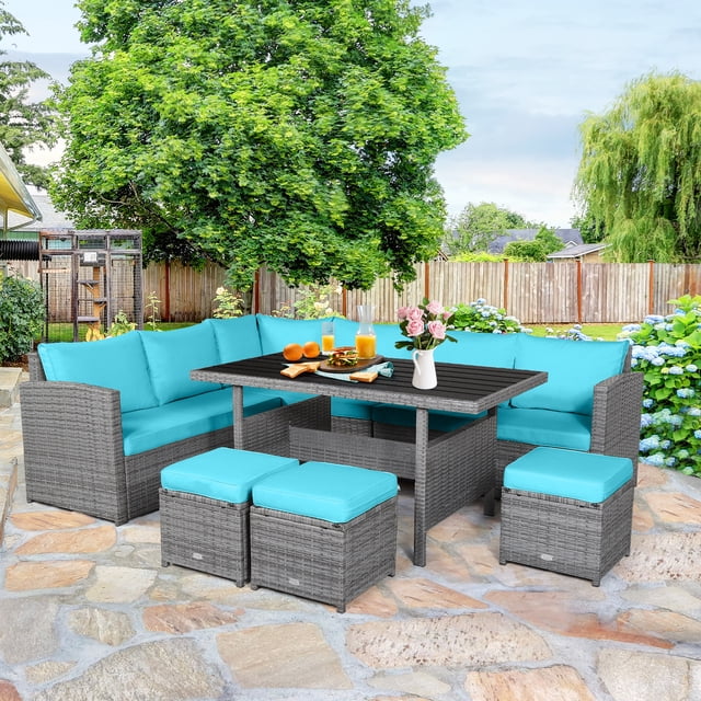Patiojoy 7-Piece Wicker Patio Furniture Set featuring a mix grey rattan frame and turquoise cushions. Includes 3 corner chairs, 3 ottomans, and a rectangular table with a plastic wood top. The set is arranged on a stone patio in a backyard with lush greenery and flowers, showcasing its suitability for outdoor gatherings.