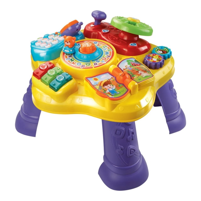 VTech Table d'Apprentissage Magic Star Jaune avec Pattes Violettes, Comprenant six Activités Interactives, Dont un Volant Pivotant, des Boutons Musicaux Lumineux, un Téléphone Factice et un Livre d'Apprentissage Électronique. Conçue pour les Enfants de 6 Mois à 3 Ans, Elle Prend en Charge l'Apprentissage de l'Anglais et de l'Espagnol et Peut Servir de Jouet de Jeu au Sol en Enlevant les Pattes.