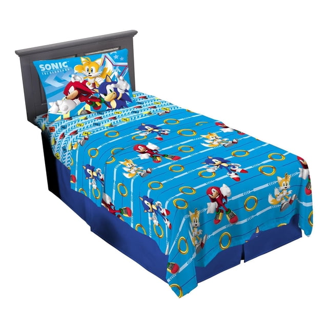 Sonic "Speed Freak" Twin Sheet Set with bright blue microfiber fitted and flat sheets and pillowcase featuring Sonic the Hedgehog characters Sonic, Tails, and Knuckles in action poses with golden rings and white arrow patterns, designed for kids' bedrooms and easy machine washing.