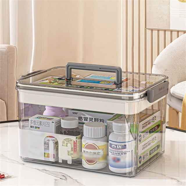 Storage Box Transparent Kit Storage Items Storage Transparent Multi Compartment Storage Box For Items Household Large Capacity Storage Box, made of durable PET plastic with a grey handle for portability. The box features a two-layer design for categorized storage, with the upper layer for smaller items and the lower layer for larger items, such as medications or household supplies. The transparent material ensures easy visibility of contents, while the secure buckle keeps items safe during transport. Displayed on a white table in a home environment.