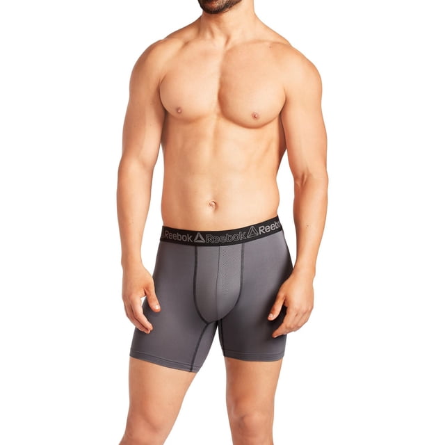 Reebok Men's Stretch Boxer Briefs, 5 Pack shown on a male model from mid-thigh to chest, featuring dark grey breathable stretch fabric with contour mesh pouch and black elastic waistband branded with Reebok logos, designed for moisture-wicking, airflow, and flexible all-day comfort.
