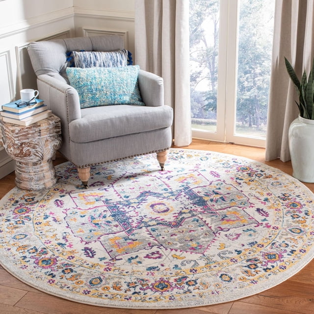 Safavieh Evoke Westley Traditional Area Rug, round with a multicolor floral and geometric pattern in blue, yellow, purple, and gray on a light background, power-loomed polypropylene frieze for durability, placed on hardwood floor under a gray armchair with blue cushions near a window with beige curtains, ideal for adding style and comfort to living areas.