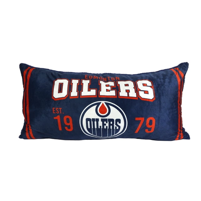 NHL Edmonton Oilers Body Pillow, 18" x 36", navy blue rectangular pillow with orange stripes on the sides, featuring the Edmonton Oilers name in white and orange, the official Oilers logo with a blue oil drop inside a white circle, and 'EST. 1979' in orange, made of soft micro-mink fabric filled with recycled polyester, suitable for bedding support and fan use.