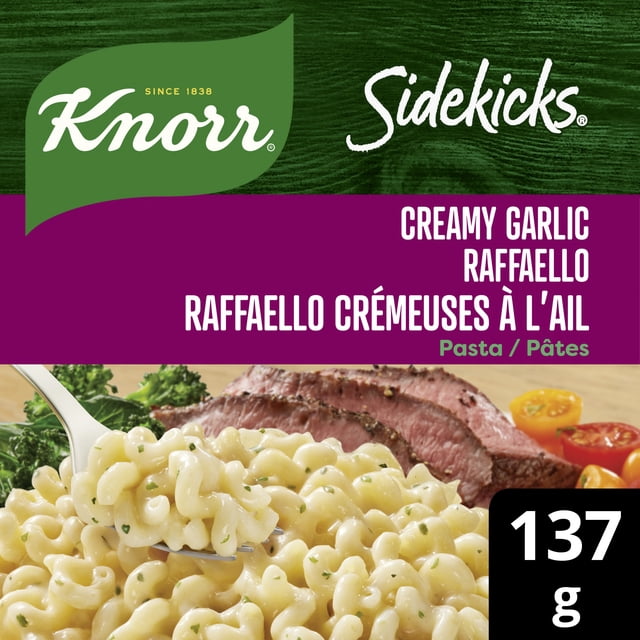 Knorr Sidekicks Pâtes Crémeuses à l'Ail Raphaello, Accompagnement de Pâtes, Emballage Montrant des Spirales de Pâtes Crémeuses à l'Ail et au Parmesan avec des Herbes sur une Fourchette, Servies avec un steak Tranché et des Tomates Cerises, Étiquetées 137 g avec Texte Bilingue Anglais-Français.