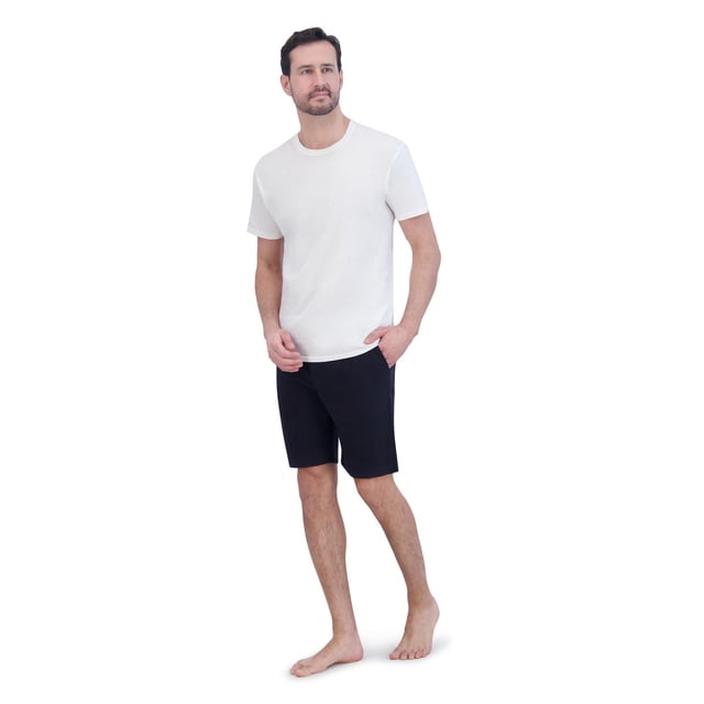 Hanes 2pk sleep short worn by a male model standing barefoot in a relaxed pose, featuring black French terry knit sleep shorts with side pockets and a contrast waistband with drawstring, paired with a plain white short-sleeve crew neck t-shirt, suitable for sleepwear and lounging.