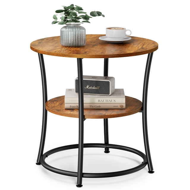 VASAGLE Side Table, 2-Tier Round End Table with a rustic brown particleboard top and lower shelf, supported by a black steel frame. The table measures 21.7 inches in diameter and 21.7 inches in height, featuring adjustable feet for stability. Shown in a living room setting with a plant, coffee cup, and books on the tabletop, and additional books and a speaker on the lower shelf.