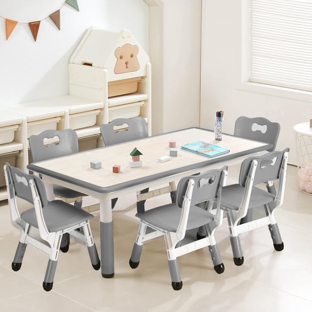 BeesClover Kids Table and 6 Chairs Set with a height-adjustable grey table and six ergonomically designed chairs featuring curved backrests. The graffiti desktop encourages creativity, while non-slip legs ensure stability. Perfect for arts, crafts, and activities for children aged 2-10. Displayed in a bright playroom with organized storage bins and toys.