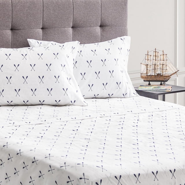 Safdie & Co. Sheet Sets 4PC D Printed Microfiber Paddles with white microfiber flat sheet, fitted sheet, and two pillow shams featuring a navy blue paddle print, displayed on a bed with a grey tufted headboard and a side table holding a model ship.