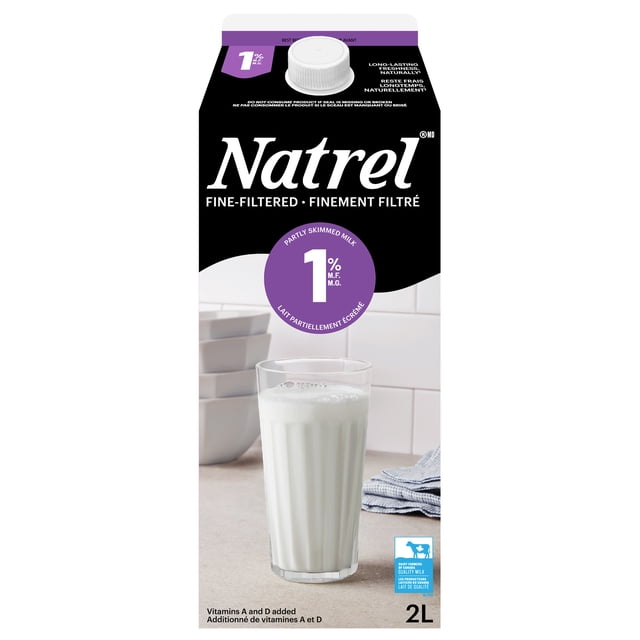 Natrel Fine-filtered 1% Milk 2L carton with black and white packaging and a purple 1% partly skimmed milk label, shown with a clear glass of milk on a kitchen counter alongside stacked white bowls and a folded blue towel, featuring added vitamins A and D for freshness.