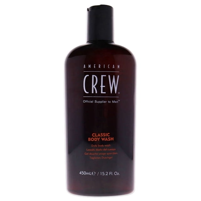 Classic Body Wash by American Crew for Men in a 15.2 oz bottle. The dark amber bottle features the American Crew logo and product details in white and orange text. This body wash is designed to gently cleanse and nourish skin with ingredients like glycerin, aloe, vitamins A and E, tea tree oil, and ginseng extract. It leaves a refreshing scent and is suitable for dry skin.