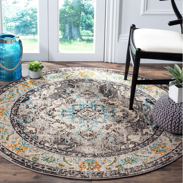 Safavieh Monaco Toria Traditional Area Rug, round with a power-loomed polypropylene pile in beige, brown, turquoise, and orange distressed Persian pattern, placed on hardwood floor near glass doors with natural light, styled with a black chair with white cushion and small potted succulents, ideal for adding Bohemian-chic accent to home interiors.