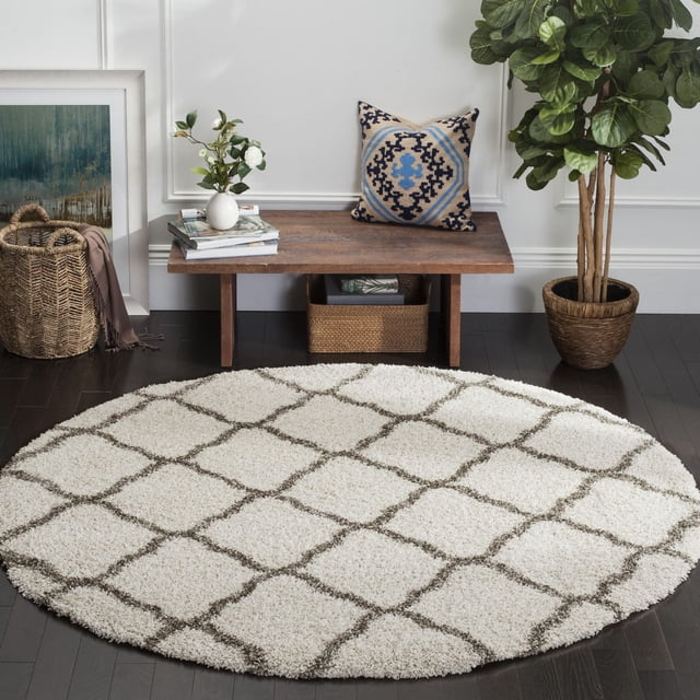 Safavieh Hudson Tapis Shag Géométrique Aliné, Rond avec une pile Shag Synthétique Peluche Blanche Présentant un Motif Treillis Géométrique Marocain Gris, Placé sur un Plancher de Bois Franc Foncé dans une Pièce Moderne avec un Banc en Bois, un Coussin Décoratif, une Plante en Pot et un Panier Tressé, Idéal pour Ajouter une texture Douce et un accent aux Aires de Vie.