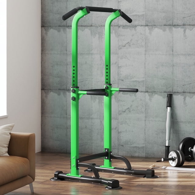 SogesPower Adjustable 82.7"H Pull up Bar Power Tower Multifunctional Fitness Station for Home. A green and black power tower with adjustable height from 65" to 82.9", featuring non-slip grips and a sturdy metal frame. Designed for pull-ups, dips, chin-ups, push-ups, and knee raises, it supports up to 330lbs. Shown in a modern home gym setting with a concrete wall and fitness equipment in the background.