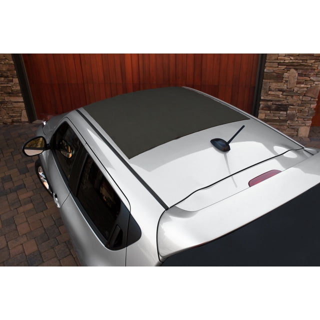 Rightline Gear Non-Skid Roof Pad measuring 34” x 39” installed on a silver car roof, shown from a high rear 3/4 angle. The dark grey pad prevents shifting of car top carriers and protects the vehicle’s roof surface. The car is parked on a stone-paved driveway with a wooden garage door and stone wall background.
