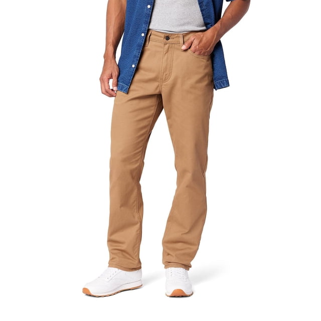 Levi Strauss Signature™ Men's Athletic Jeans in tan denim with stretch fabric, shown on a male model from waist to feet, featuring an athletic fit with extra room in seat and thigh, tapered leg, zip fly, and 5-pocket styling, paired with white sneakers and a blue shirt over a grey tank top on a white background.