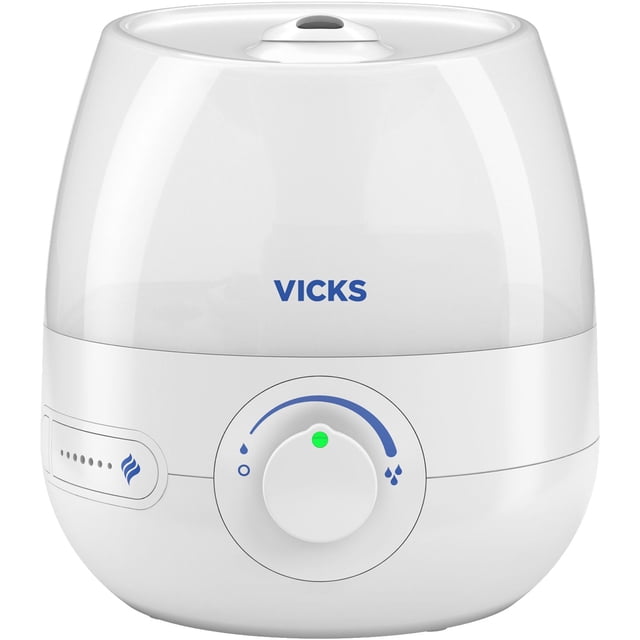 Vicks VUL525C Mini FilterFree Ultrasonic Cool Mist Humidifier with a white base and translucent water tank, front view showing the Vicks logo, a central dial for adjustable mist output, and a side panel with mist level indicators, suitable for small rooms and filter-free use.
