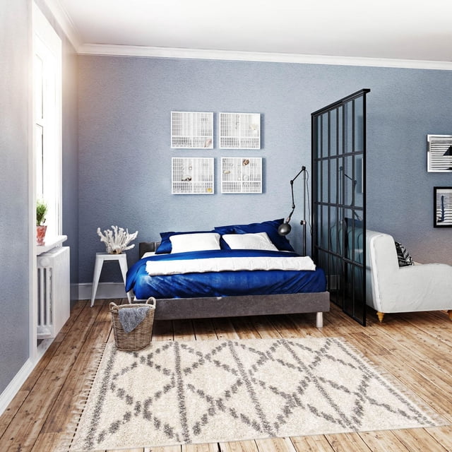 ECARPET Super Soft for Living Room & Bedroom Grammercy Liv Cream Shag area rug with cream base and gray diamond geometric pattern on wooden floor in a modern bedroom featuring a blue bed with white pillows, a white side table with coral decor, and a black metal room divider.