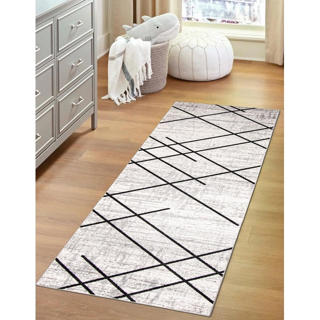 ECARPET washable abstract striped area rug and runner for living room, bedroom, hallway with low pile polyester in white and grey tones featuring intersecting black lines, placed on light hardwood floor near a grey dresser, woven basket with white throw and shark plush, and white stitched pouf, ideal for high traffic areas.