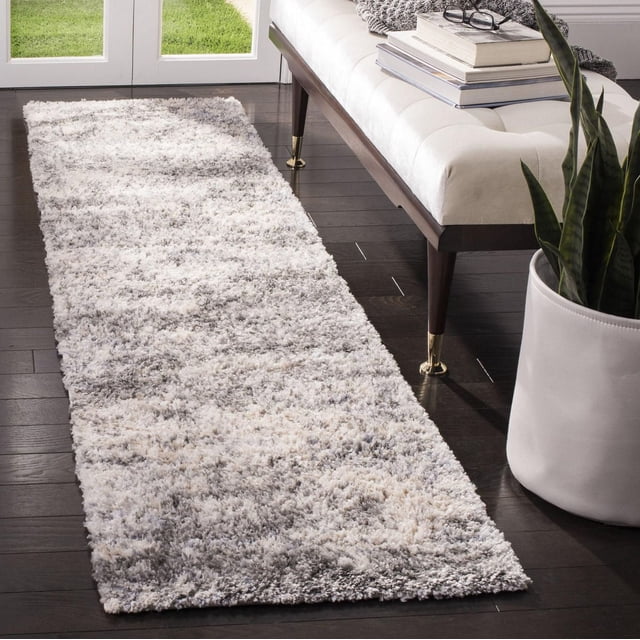 SAFAVIEH Berber Harold Tapis Shag Abstrait en Peluche pour Aire en Tons Gris et Crème avec Faible Poil Duveteux et Motif tribal Abstrait, Posé sur un Plancher de Bois Franc Foncé à Côté d'Un Banc Capitonné Blanc avec Pattes à Dessus en Laiton et un Cache-Pot Blanc avec Plante Serpent, Convient pour Ajouter Chaleur et texture aux Zones de Tapis d'Accent.