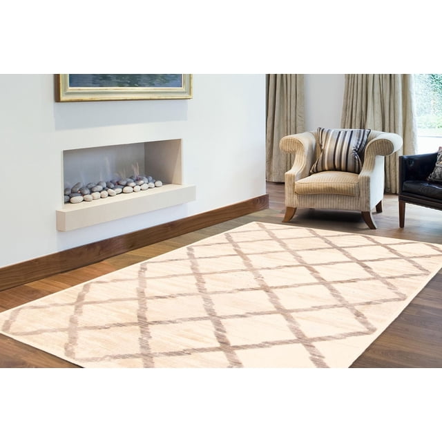 ECARPET Area Rug for Living Room and Dining Room Kasbah Ivory 6'3" x 9'6" featuring a Moroccan-inspired lattice pattern in light brown on an ivory background, laid on hardwood flooring. Positioned near a beige armchair with a striped cushion and a modern recessed fireplace with decorative stones, suitable for enhancing living or dining room comfort and style.