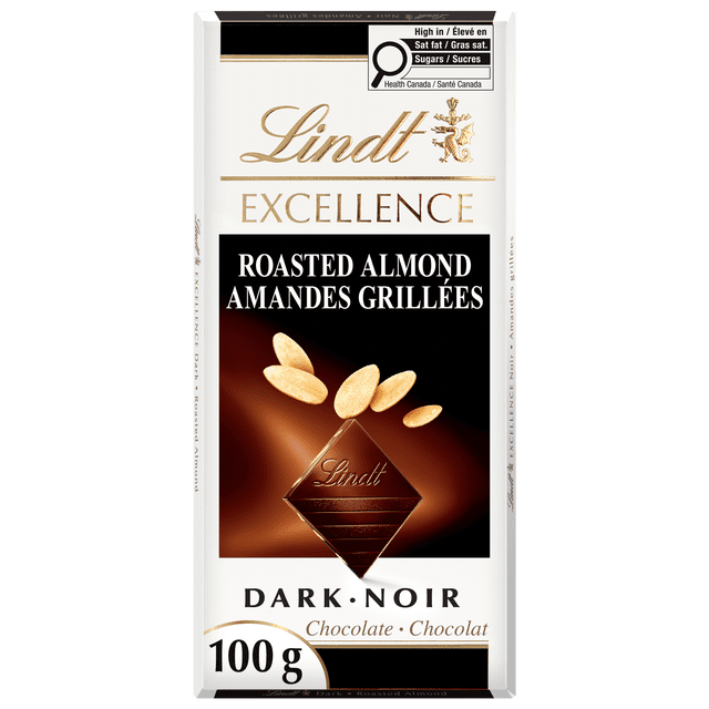 Lindt EXCELLENCE Roasted Almond Dark Chocolate Bar, 100 g, with white and gold packaging featuring the Lindt logo, a dark chocolate square embossed with 'Lindt,' roasted almond slivers above it, bilingual English and French text, and a Health Canada nutrition label for saturated fat and sugars.