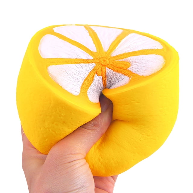 toy Squishy Half Fresh Lemon Slow Rising Key Chains Stress Fruit Ballchain Charm Toy. A bright yellow squishy novelty toy shaped like half a lemon with detailed white and orange pulp design, being squeezed by a hand. Made from elastic environmentally friendly PU material, it is slow rising and scented, ideal for stress relief and fun. Suitable for party decorations, children's toys, holiday gifts, and gag gift exchanges.