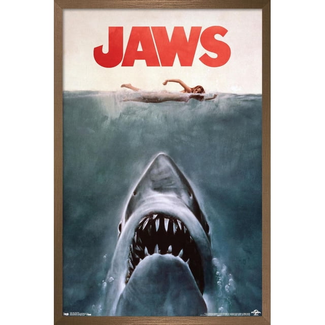 Jaws - One Sheet Wall Poster, 22.375" x 34" showing a front-facing great white shark with open jaws and sharp teeth swimming upward beneath a swimmer on the water surface, with bold red JAWS title above, printed on glossy poster paper ideal for home décor and wall art, often used to add dramatic style to bedrooms or offices.