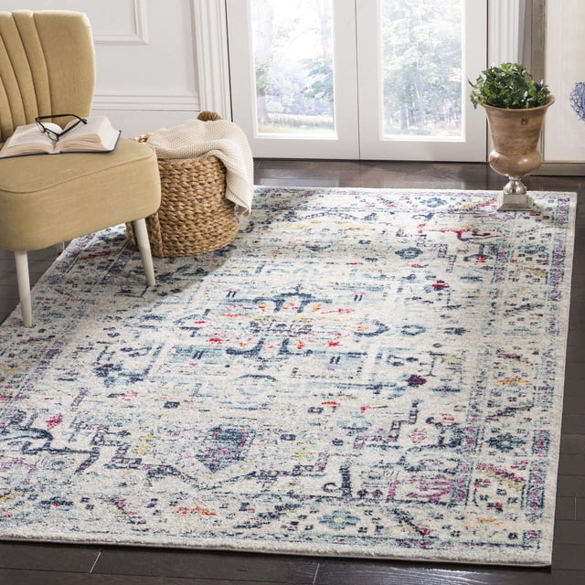 Safavieh Madison Dahila Floral Bordered Area Rug with a light base featuring multicolored floral and geometric patterns in blue, red, and yellow, bordered by a classic design, placed on dark hardwood floors in a bright room, partially under a beige accent chair and beside a woven basket with a cream throw, suitable as a transitional accent rug for contemporary home decor.