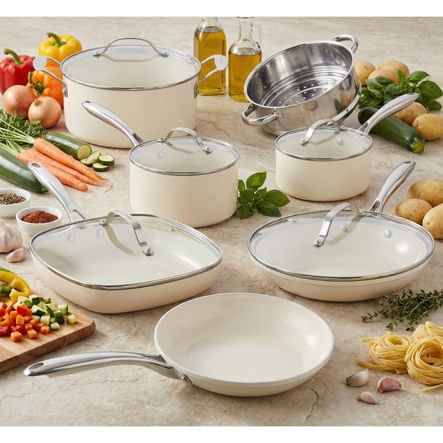 Gotham Steel Cream 12 Piece Ultra Nonstick Ceramic Cookware Set with Stay Cool Handles, featuring a complete collection of skillets, saucepans, a stock pot, a deep square pan, and a stainless steel steamer. The cookware is crafted from lightweight aluminum with a triple-layer ceramic nonstick interior for easy food release and healthier cooking. Each piece includes stay-cool handles and is oven safe up to 500°F. The set is displayed on a kitchen countertop surrounded by fresh vegetables, herbs, and cooking oils, emphasizing its versatility and suitability for various stovetops, including gas, electric, ceramic, and halogen.
