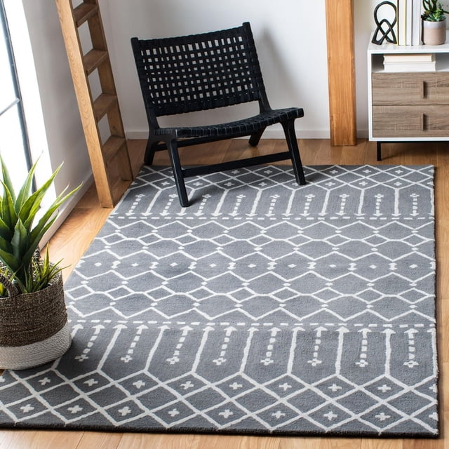 Safavieh Himalaya Darin Geometric Area Rug in grey with white geometric patterns, crafted from 100 percent hand-loomed wool, placed on a hardwood floor under a black woven lounge chair, beside a wooden ladder and a white and wood side cabinet with a potted green plant, ideal for accentuating modern living spaces.