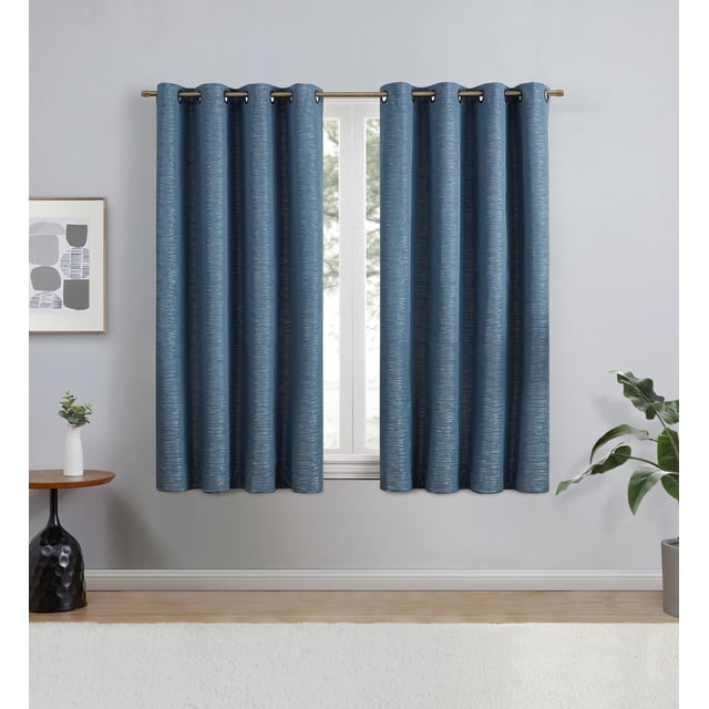 Eclipse Avery 63" grommet blackout window curtains panel in indigo blue textured polyester fabric hanging on a gold curtain rod over a window in a room with light grey walls, wooden side table with a white vase and plant, and a potted green plant, suitable for light reduction and privacy.
