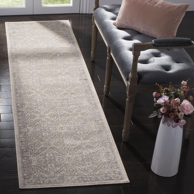 SAFAVIEH Brentwood Brandy Floral Geometric Area Rug runner featuring a muted beige and gray floral geometric pattern in soft synthetic yarn, placed on dark hardwood flooring beside a gray tufted bench with wooden legs and a pink pillow, near a white vase with pink and burgundy flowers, ideal for adding warmth and style to hallways or entryways.